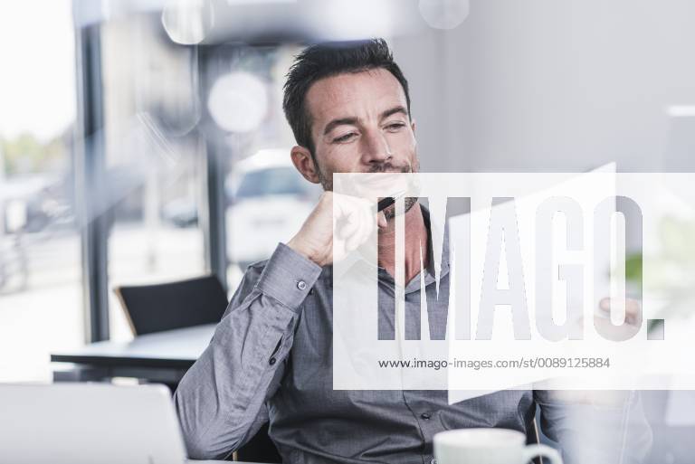 Businessman sitting in office, reading a letter model released Symbolfoto property released UUF15838