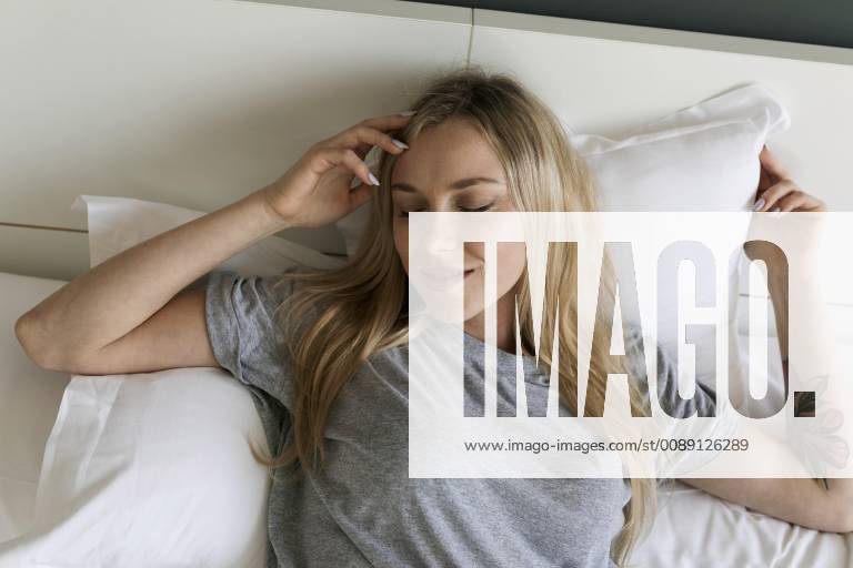 Smiling blond young woman lying in bed model released Symbolfoto property released VABF01711