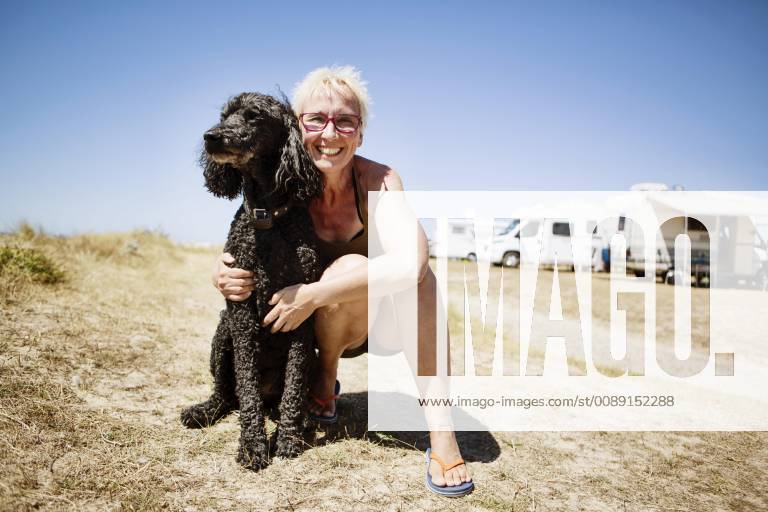 Woman embraces her dog king poodle at a campsite Portbail Normandie France Europe