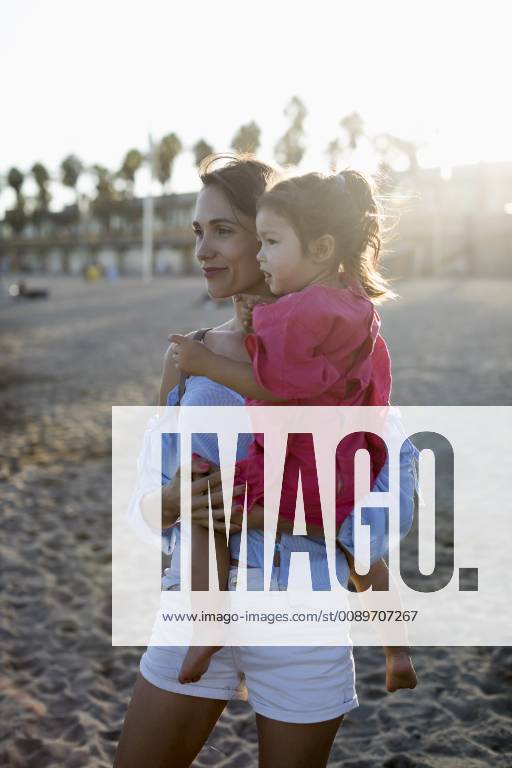 Mother and daughter standing on the beach at sunset model released Symbolfoto MAUF01900