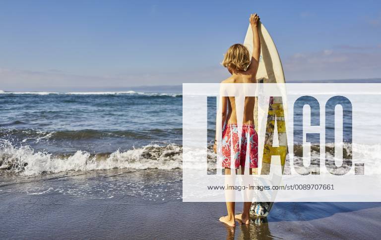 Chile, Pichilemu, boy standing at the sea with surfboard model released Symbolfoto SSCF00120