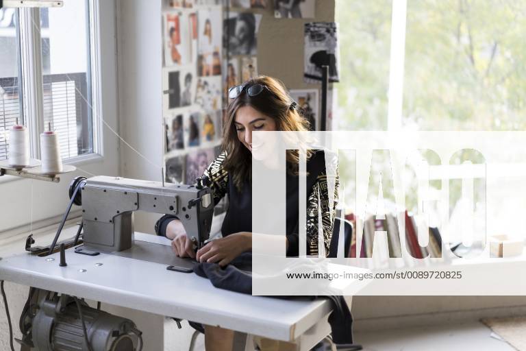 Smiling young fashion designer using sewing machine in her atelier model released Symbolfoto property released AFVF02054