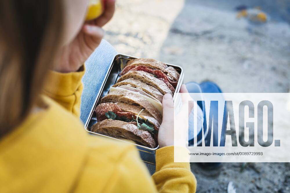 IMAGO Creative: Gesellschaft, Schule, Schulanfang Lifestyle, Haushalt, Küche, nachhaltig und plastikfrei Girl with lunch box sitting on the beach in autumn model released Symbolfoto HMEF00082