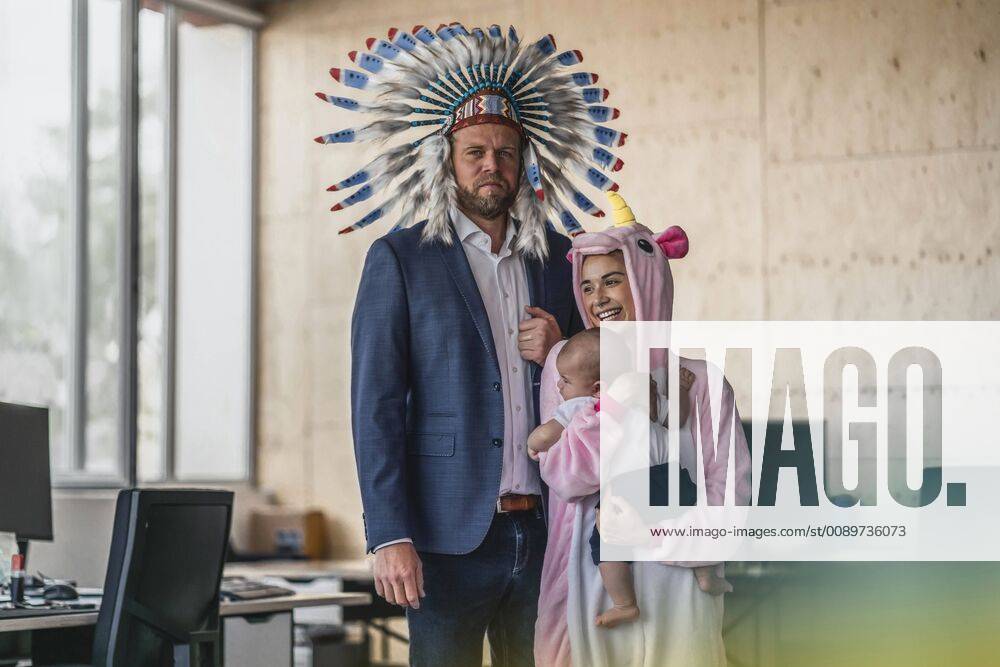 Man and woman, dressed as Indian and unicorn, standing in office, woman holding baby in her arms model released Symbolfoto property released RIBF00869