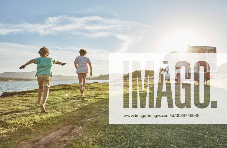 Chile, Talca, Rio Maule, two boys running on meadow beside camper at lake model released Symbolfoto property released SSCF00125