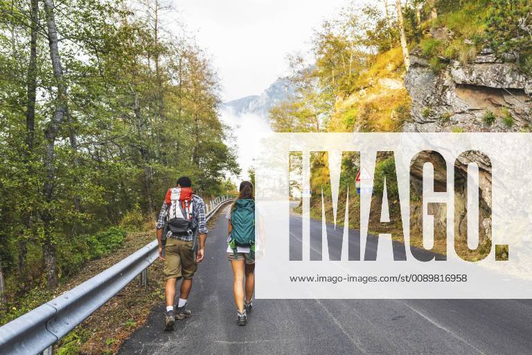 Italy, Massa, rear view of young couple walking on asphalt road in the Alpi Apuane mountains model released Symbolfoto WPEF00911