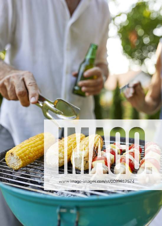 Corn cob and meat skewer on grill at barbecue in garden model released Symbolfoto property released ZEDF01598