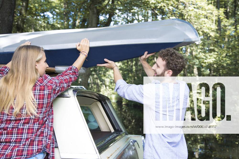 Smiling young couple taking canoe from car roof model released Symbolfoto FKF02804
