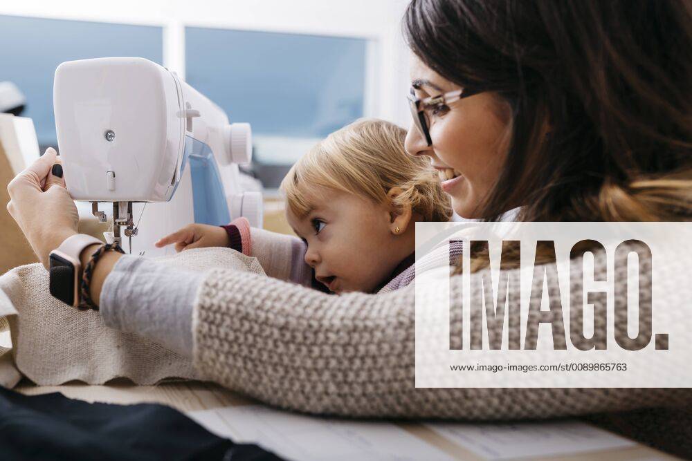 Happy mother with little daughter at home using sewing machine model released Symbolfoto property released JRFF02086