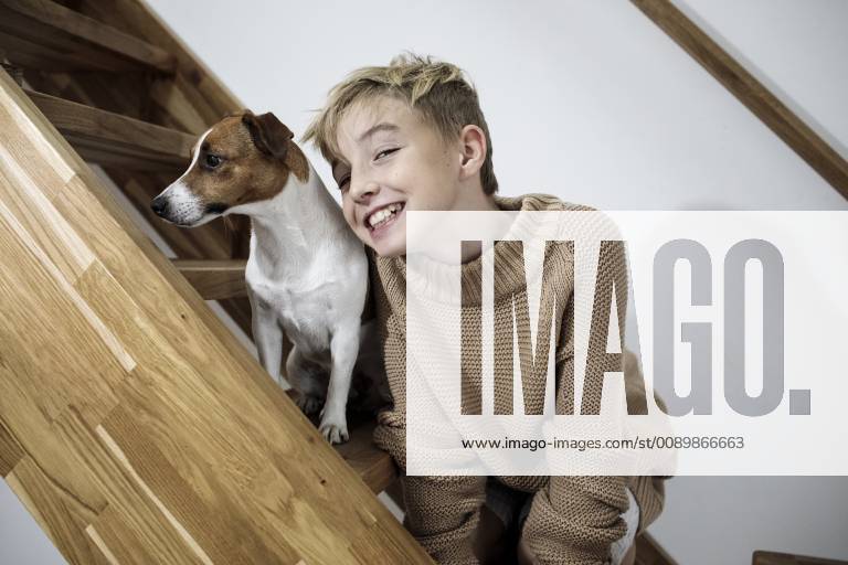 Portrait of grinning boy and his Jack Russel Terrier on stairs at home model released Symbolfoto property released KMKF00650