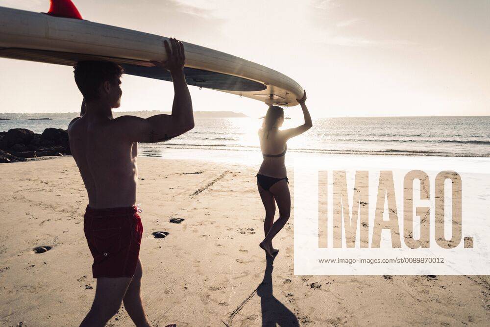 France, Brittany, young couple carrying an SUP board on the beach together model released Symbolfoto UUF15917