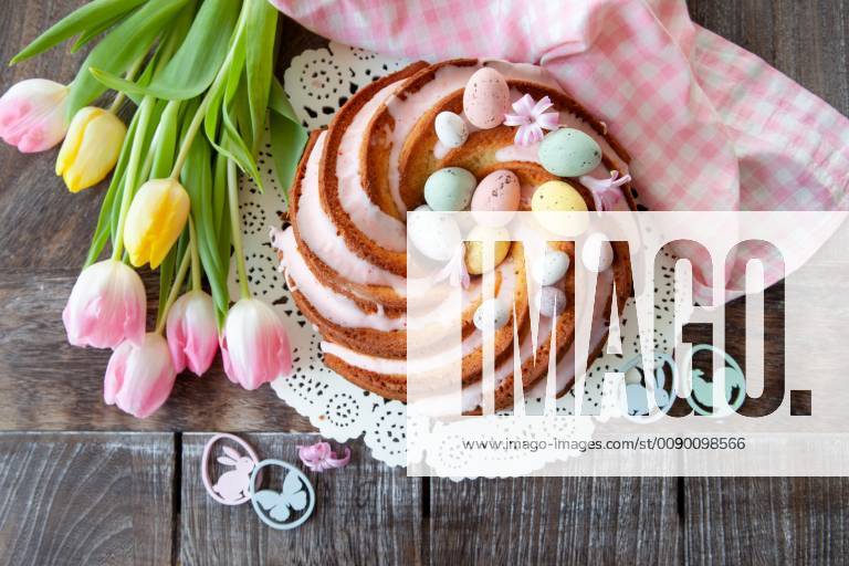 Delicious Gugelhupf with Easter eggs and pink icing Tasty bundt cake with pink frosting 1079705478
