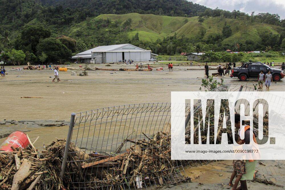 (190317) -- SENTANI, March 17, 2019 -- A mother holds her child near a collapsed fence after flash floods in Sentani, Indonesia, on March 17, 2019. Sixty-three bodies have been retrieved after flash floods hit Indonesia s easternmost Papua province on Saturday night, and a search and rescue operation is still ongoing for dozens still missing, a rescue team member said on Sunday. ) INDONESIA-SENTANI-FLASH FLOOD Ikha