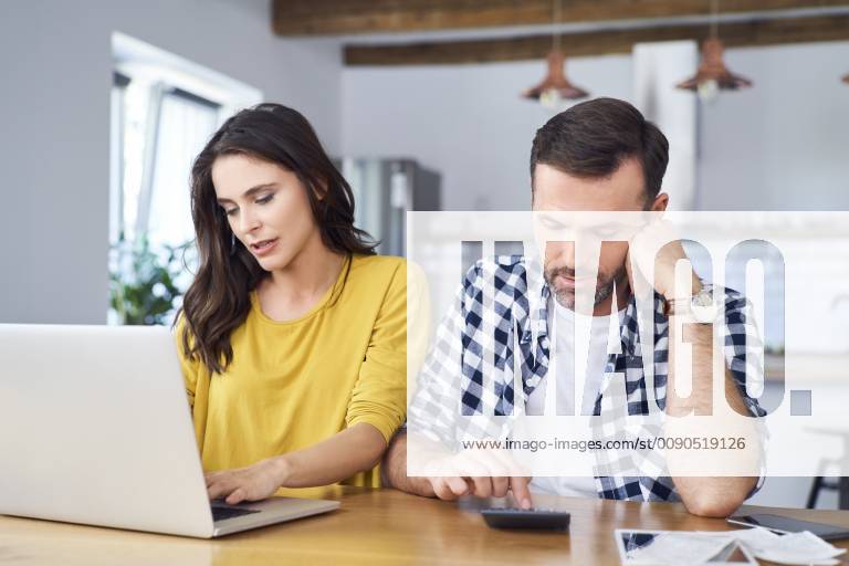 Worried couple sitting at dining table, using laptop, checking finances model released Symbolfoto property released BSZF00874
