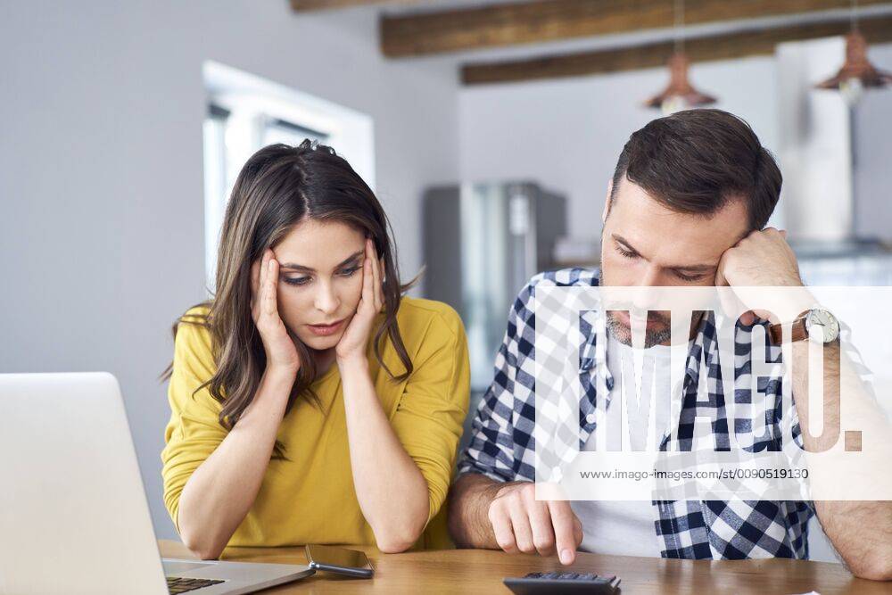 Worried couple sitting at dining table, using laptop, checking finances model released Symbolfoto property released BSZF00875