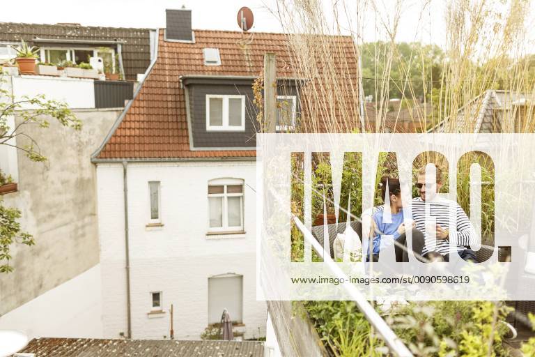 Young couple relaxing on their balcony, sitting on couch model released Symbolfoto property released PESF01158