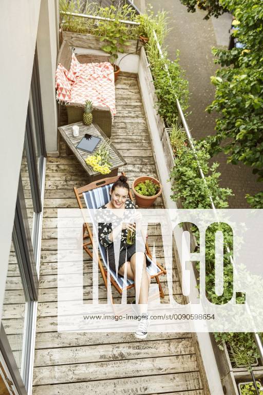 Young woman sitting in deck chair, relaxing on her balcony model released Symbolfoto property released PESF01186