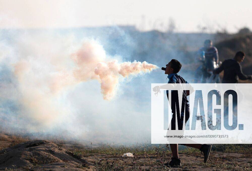 KW15 (190412) -- GAZA, April 12, 2019 -- A Palestinian protester holds a tear gas canister fired by Israeli troops in his mouth during clashes on the Gaza-Israel border, east of al-Bureij refugee camp in central Gaza, on April 12, 2019. The Israeli army shot dead a Palestinian boy on Friday and wounded dozens during clashes with hundreds of Palestinian demonstrators in eastern Gaza Strip, close to the border with Israeli, according to medics. ) MIDEAST-GAZA-CLASHES YasserxQudih