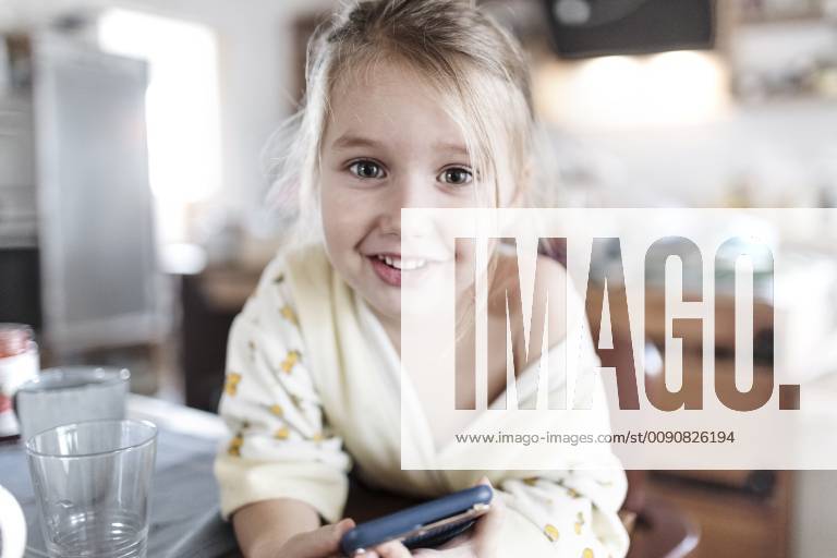 Portrait of smiling little girl with smartphone in the kitchen model released Symbolfoto property released KMKF00718