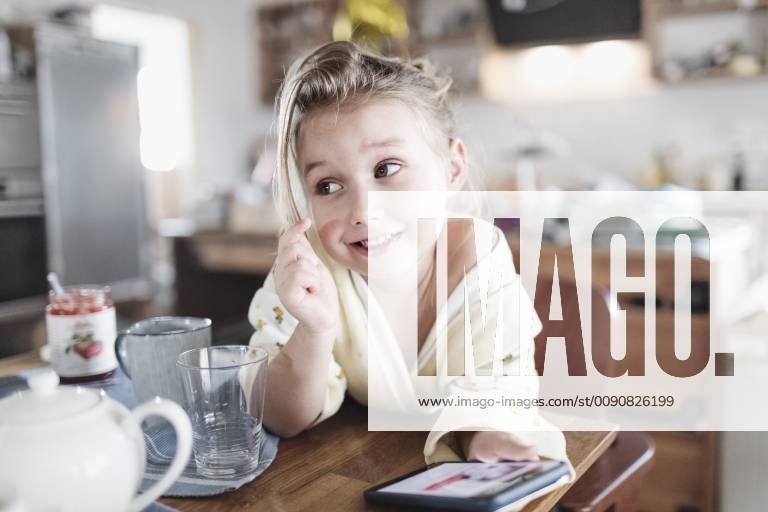 Portrait of smiling little girl with smartphone in the kitchen model released Symbolfoto property released KMKF00721