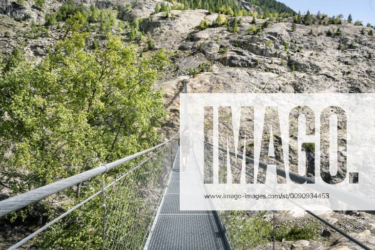 Switzerland, Valais, woman on a hiking trip in the mountains from Belalp to Riederalp on a swinging bridge model released Symbolfoto DMOF00116
