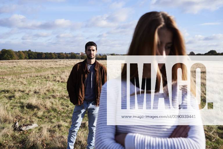 Serious young woman standing on a field with man behind her model released Symbolfoto IGGF00838