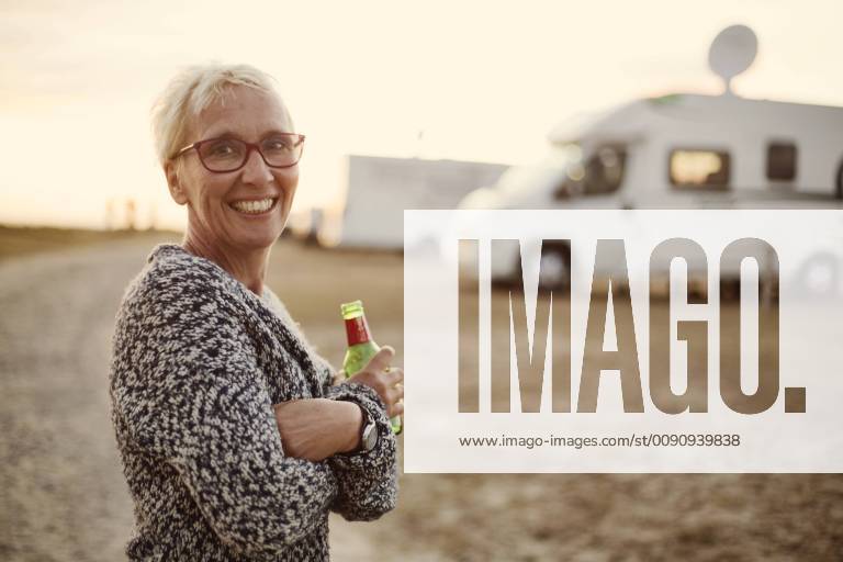 Portrait of smiling woman with beer bottle on camping ground in the evening model released Symbolfoto JATF01136
