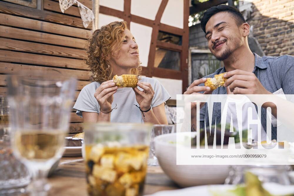 Couple eating grilled corn cobs at a backyard barbecue model released Symbolfoto property released PDF01857