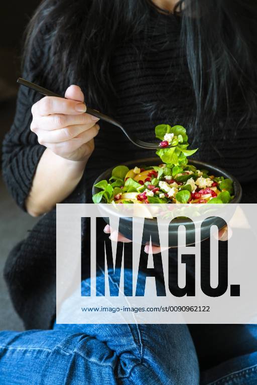 Woman eating mixed salad with lamb s lettuce, feta, pear, pomegranate seed and walnuts model released Symbolfoto SARF04106