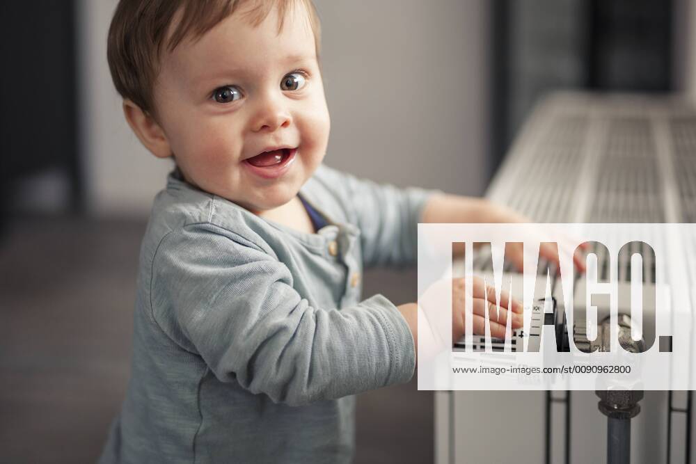 Portrait of smiling baby boy playing with thermostat of heater model released Symbolfoto property released SEBF00022