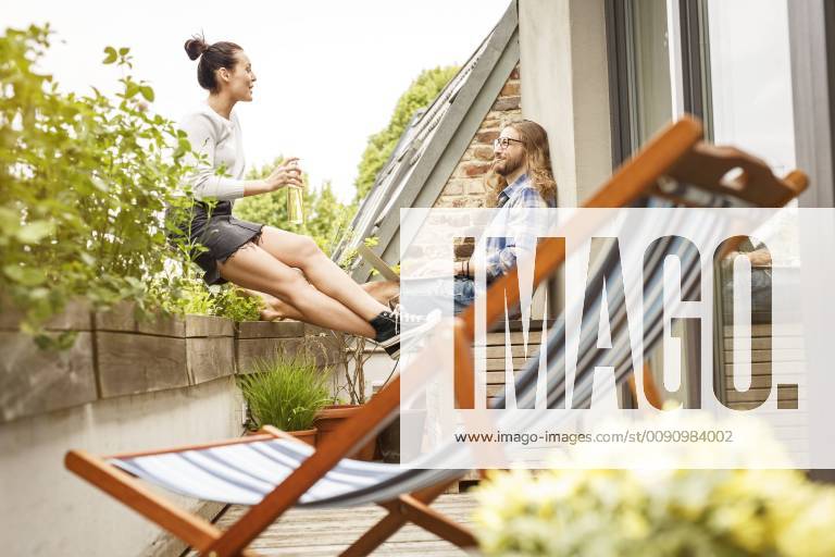 Young couple sitting on their balcony in summer, talking and using laptop model released Symbolfoto property released PESF01103