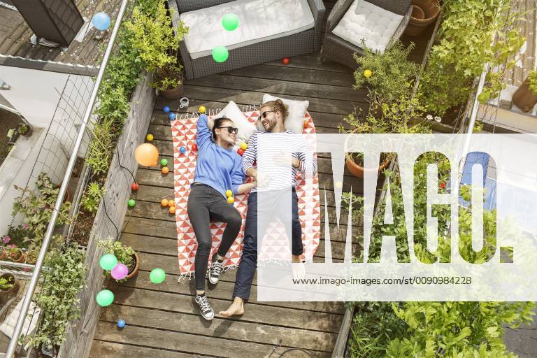 Young couple relaxing on their balcony, lying on blanket with arms around model released Symbolfoto property released PESF01171