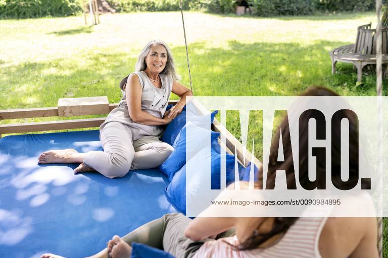 Two women relaxing on a hanging bed in garden model released Symbolfoto property released PESF01371