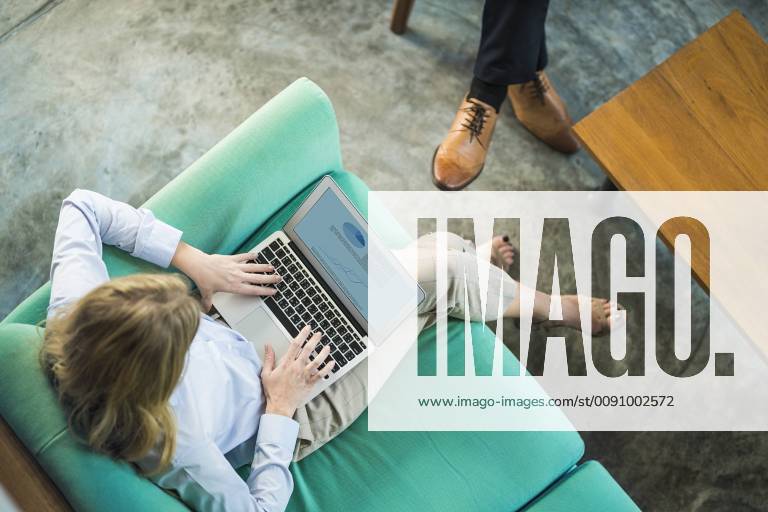 Top view of businesswoman working on laptop on turquoise couch in coworking space model released Symbolfoto property released SBOF01556