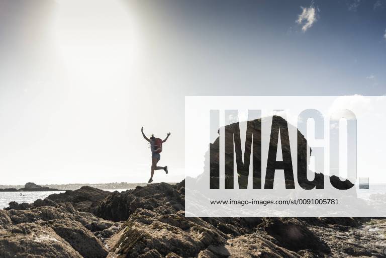 Young woman runnning and jumping on a rocky beach model released Symbolfoto UUF16458