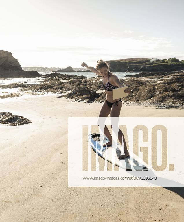 Young woman standing on surfboard, using digital tablet model released Symbolfoto UUF16482