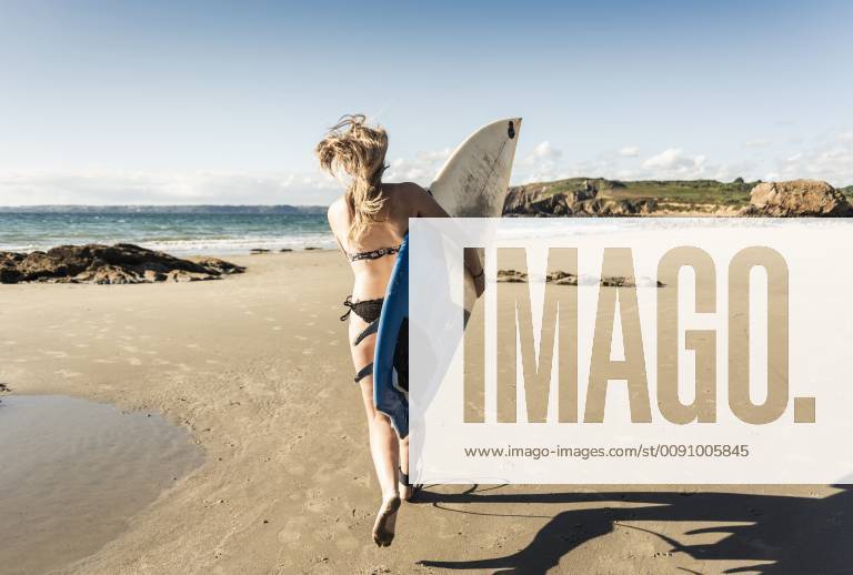 Young woman running on the beach, carrying surfboard model released Symbolfoto UUF16487
