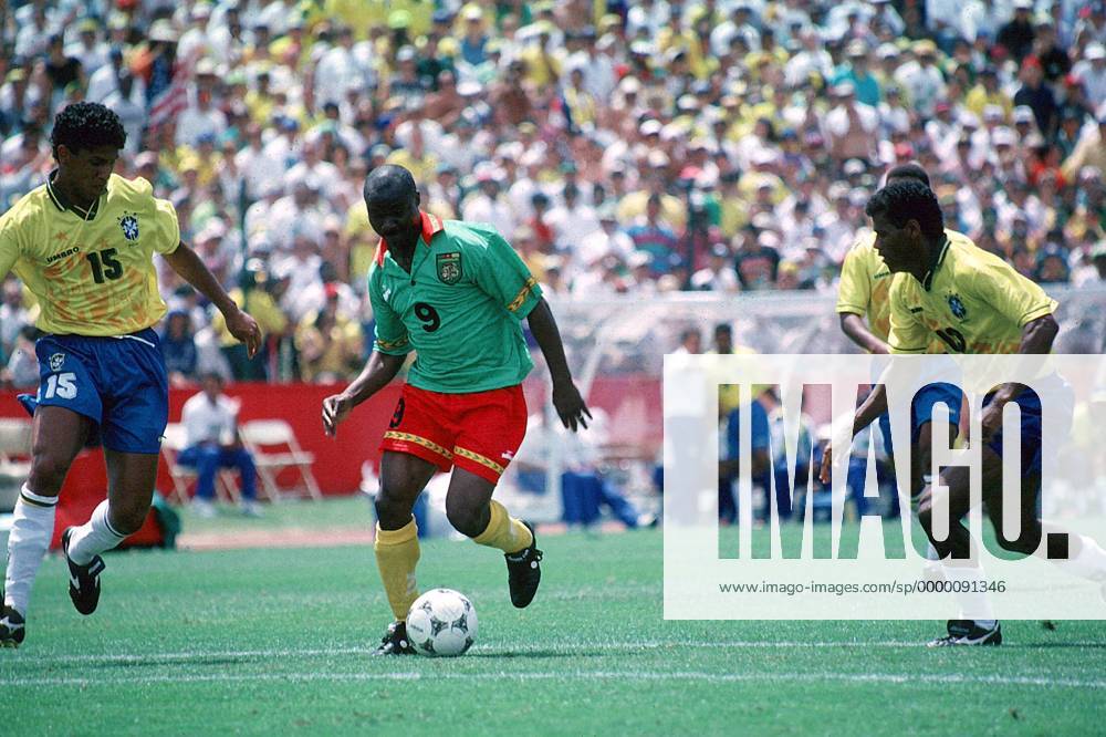 Der Kameruner Roger Milla mit Ball, verfolgt vom Brasilianer Marcio Santos (li.), re. Aldair Fußball WM Herren Länderspiel, Weltmeisterschaft 1994: Brasilien - Kamerun Gruppe San Francisco Dynamik,