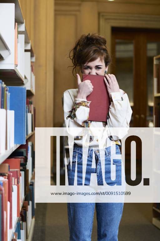 Female student reading book in a public library model released Symbolfoto IGGF01053