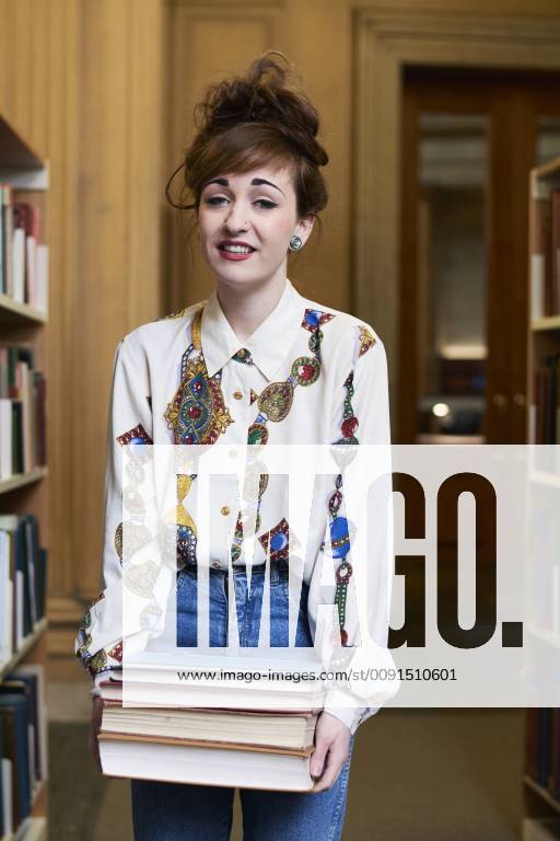 Female student with books in a public library model released Symbolfoto IGGF01056