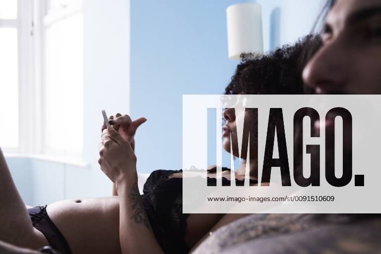 Young woman with boyfriend using cell phone in bed model released Symbolfoto property released IGGF01067