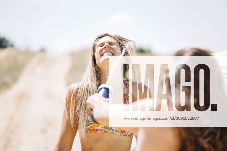 Two happy young women in bikini splashing water model released Symbolfoto OCMF00360