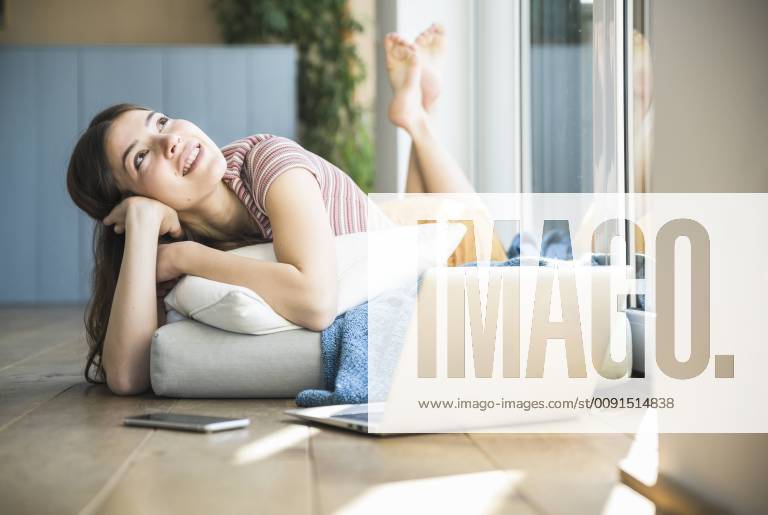 Relaxed young woman lying at the window at home with laptop model released Symbolfoto property released UUF16994
