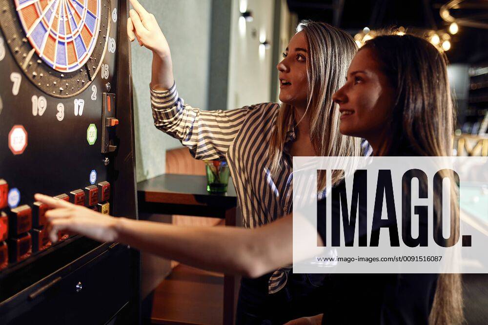 Two women playing darts setting electronic dartboard model released Symbolfoto property released ZEDF02057