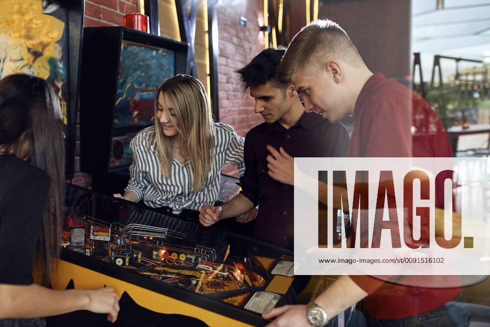 Man playing pinball watched by friends model released Symbolfoto property released ZEDF02065