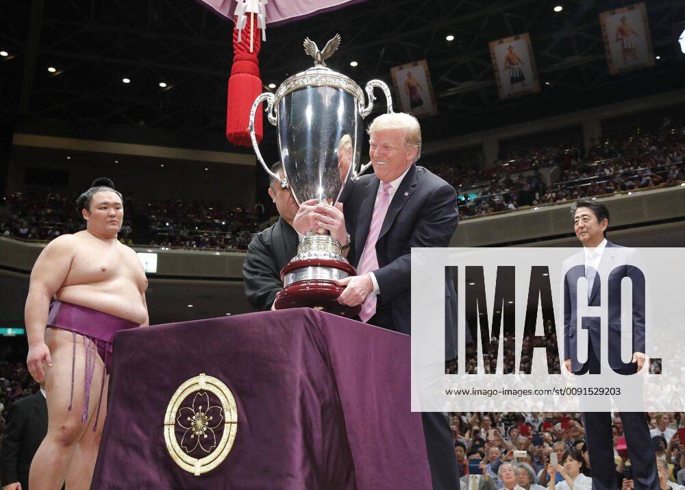 Trump in Japan U.S. President Donald Trump (C) holds a special American-made trophy before presenting it to Summer Grand Sumo Tournament winner Asanoyama (L) on the final day of the tournament at Tokyo s Ryogoku Kokugikan on May 26, 2019, as Japanese Prime Minister Shinzo Abe looks on.