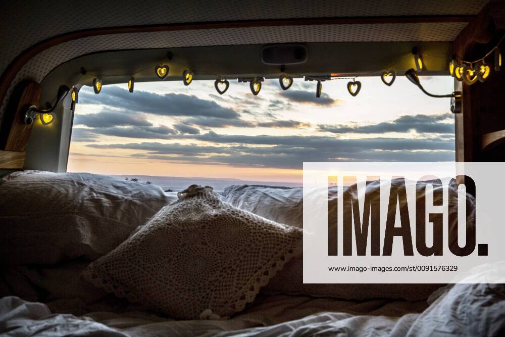 Camper van with cushion and fairy lights, view through rear window at sunset. Camper van with cushion and fairy lights, view through rear window at sunset. 57811