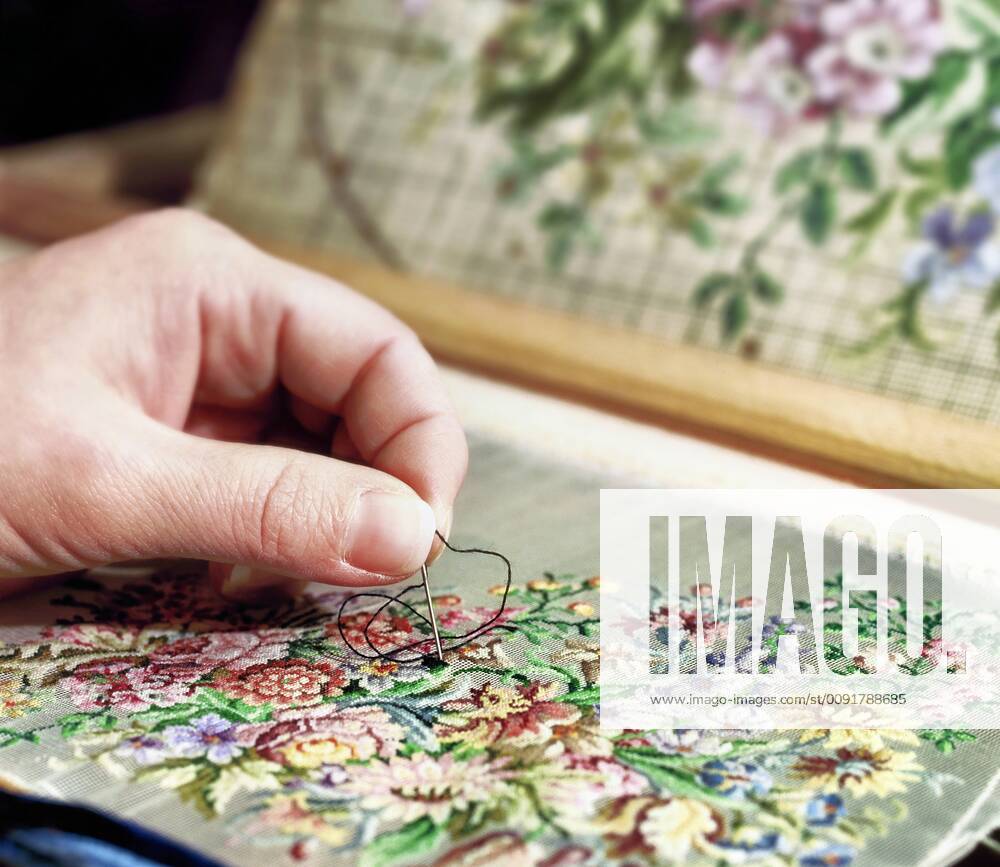 Embroidery as an old craft, close-up of a hand with an embroidery needle on an embroidery with a floral pattern.
