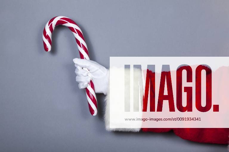 Santa Claus holds candy cane in hand