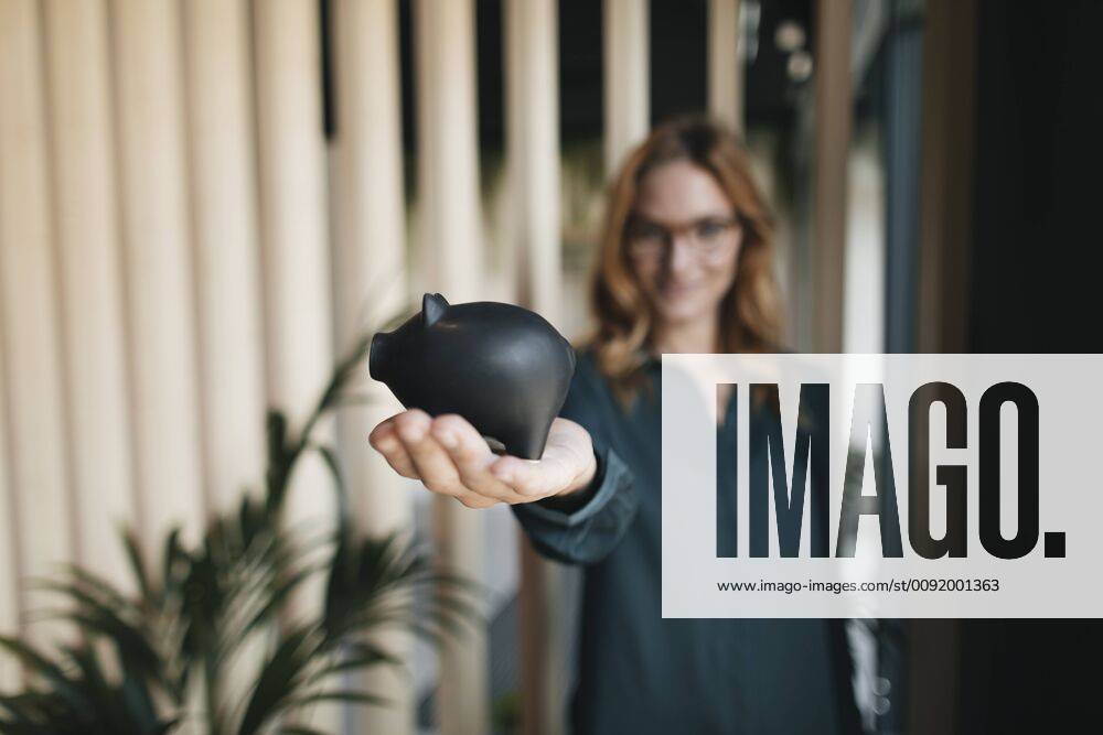 Businesswoman holding piggy bank model released Symbolfoto property released GUSF01916